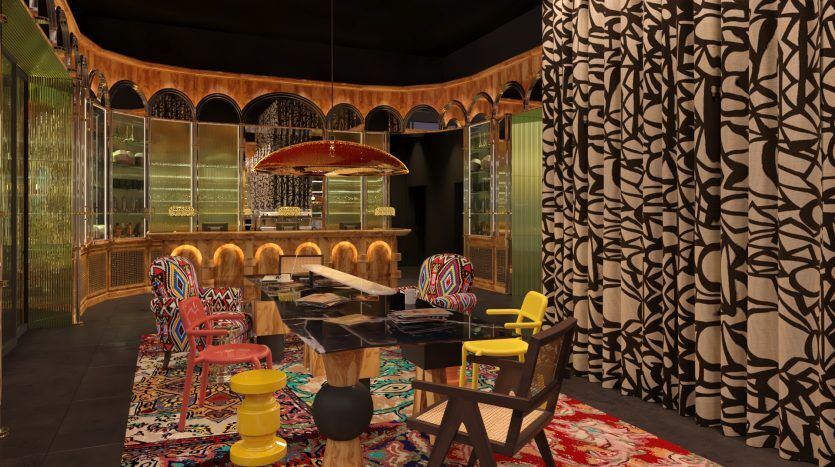Une salle à manger vibrante et éclectique dans une villa de Dubaï avec des rideaux aux motifs audacieux, des chaises colorées dépareillées, une table en bois et un bar doré orné à l'arrière sous un plafonnier élégant.