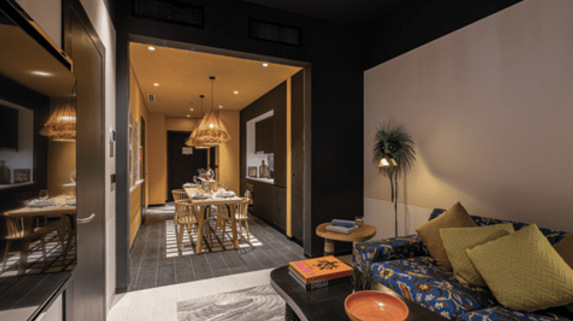 Intérieur d'appartement moderne à Dubaï avec un salon confortable doté d'un canapé à motifs et d'une décoration chic, menant à une élégante salle à manger éclairée par des suspensions.