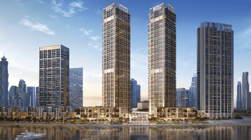 Trois grands gratte-ciel modernes au bord d'une rivière avec un horizon de la ville en arrière-plan et un petit bateau naviguant sur l'eau au coucher du soleil à Dubaï.