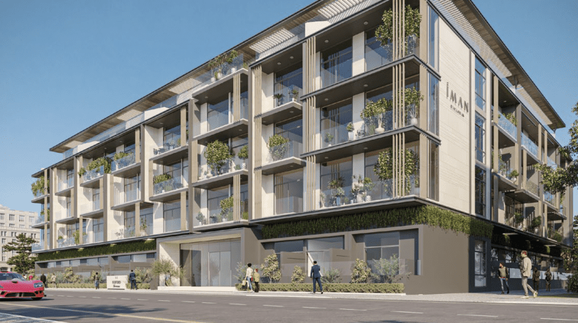 Bâtiment moderne de plusieurs étages avec une vaste verdure sur les balcons, avec des piétons et une voiture rouge dans la rue dans un cadre urbain ensoleillé, idéal pour investir à Dubaï.