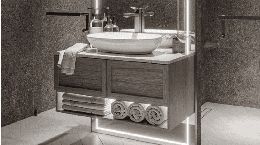 Vanité de salle de bain moderne avec finition en bois dans une villa de Dubaï, comprenant un lavabo blanc, une base éclairée par LED, des serviettes soigneusement empilées et des accessoires minimalistes.