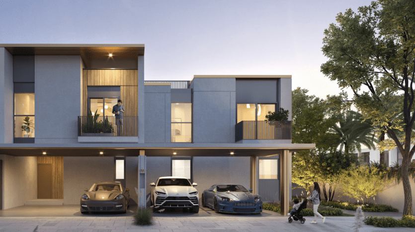 Bâtiment moderne de deux étages avec balcons à Dubaï, comprenant trois voitures garées et deux individus promenant un chien dans un espace paysager au crépuscule.