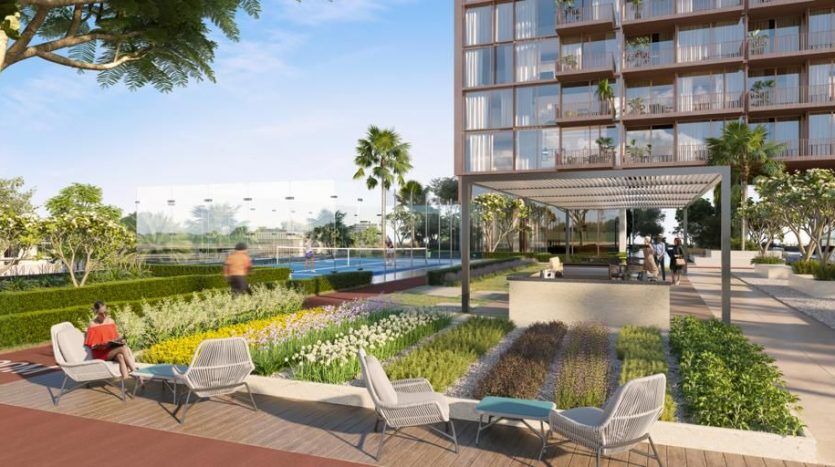 Immeuble résidentiel moderne à Dubaï avec une cour magnifiquement paysagée comprenant des coins salons, des sentiers pédestres et une variété de plantes. Les gens profitent de l’espace extérieur serein et ensoleillé.