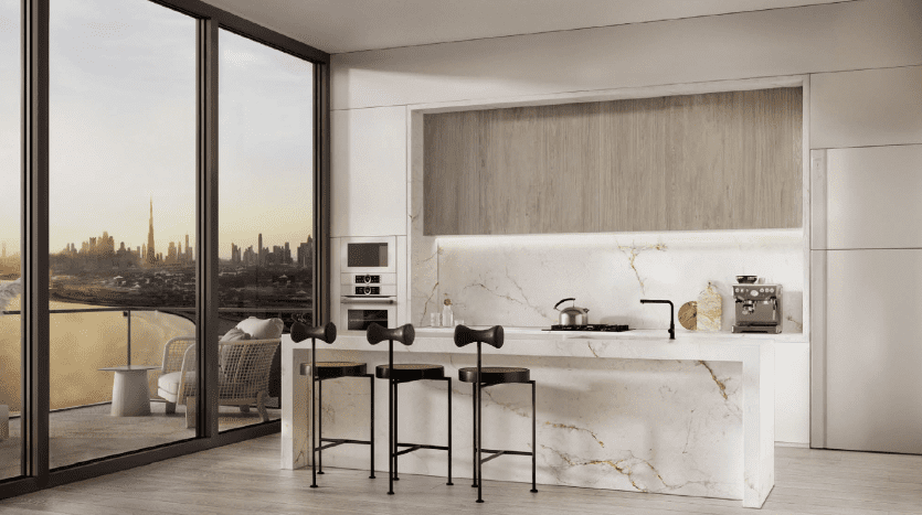 Cuisine moderne avec îlot en marbre, touches de bois et tabourets de bar dans un appartement de Dubaï donnant sur un paysage urbain à travers des baies vitrées.