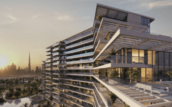 Un bâtiment moderne à plusieurs niveaux avec de vastes façades en verre au coucher du soleil, surplombant les toits de la ville de Dubaï avec un gratte-ciel proéminent en arrière-plan.