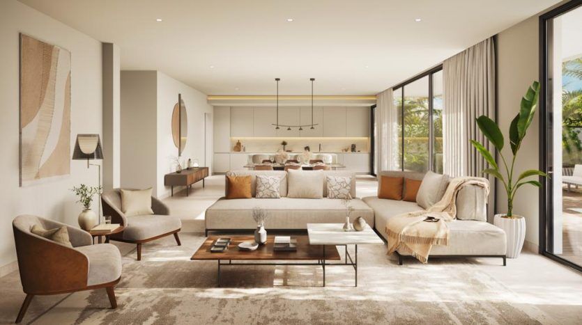 Un salon moderne et spacieux dans un appartement de Dubaï avec une décoration élégante, de grandes fenêtres et un plan ouvert se prolongeant vers une cuisine. Les tons neutres et la lumière naturelle créent une atmosphère chaleureuse et invitante.