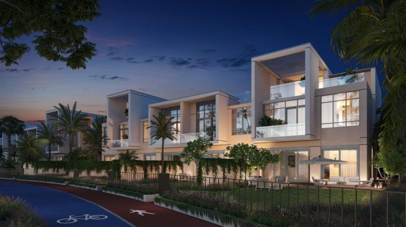 Villas modernes à deux étages à Dubaï avec de grandes fenêtres et balcons, illuminés au crépuscule, flanqués d'une piste cyclable et d'une verdure luxuriante.