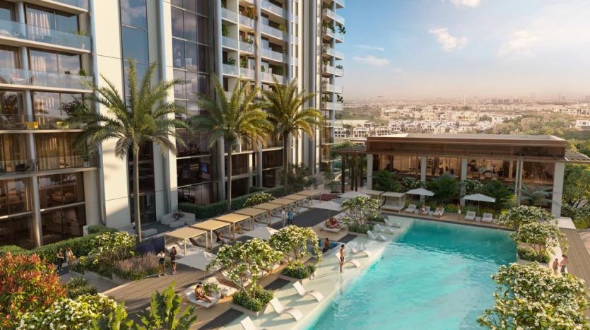 Vue d'un complexe d'appartements de luxe de grande hauteur à Dubaï, doté d'une piscine extérieure entourée de palmiers, de coins salons et d'un horizon de la ville en arrière-plan.