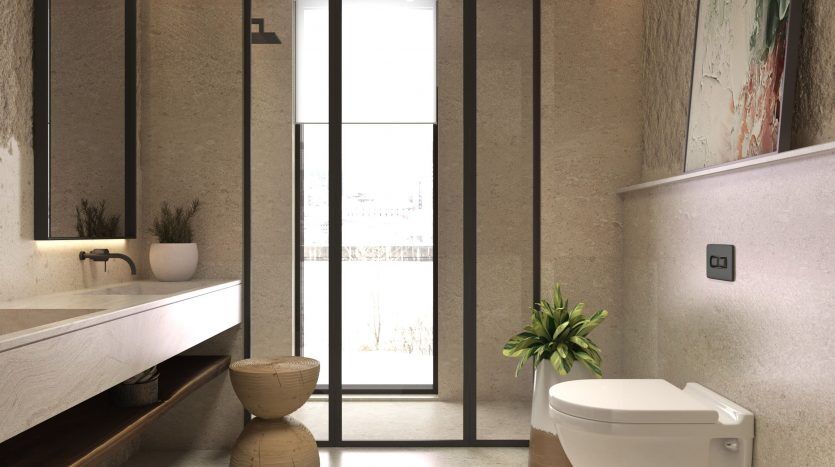 Une salle de bains moderne dans une villa à Dubaï comprenant des toilettes murales, un grand miroir avec une étagère en bois et des murs texturés naturels. Deux plantes en pot ajoutent une touche de verdure, et un grand