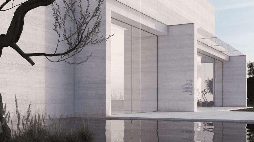 Bâtiment architectural moderne avec de grandes fenêtres en verre reflétant un plan d'eau serein, encadré par un arbre sans feuilles et une herbe luxuriante sous un ciel clair à Dubaï.
