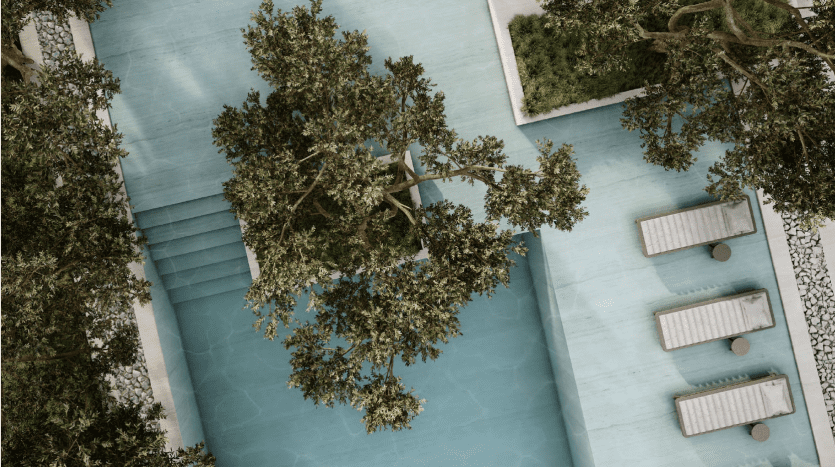 Vue aérienne d'une piscine extérieure sereine entourée d'arbres verts luxuriants et de trois chaises longues blanches soigneusement disposées le long du bord de la piscine d'un appartement de Dubaï.