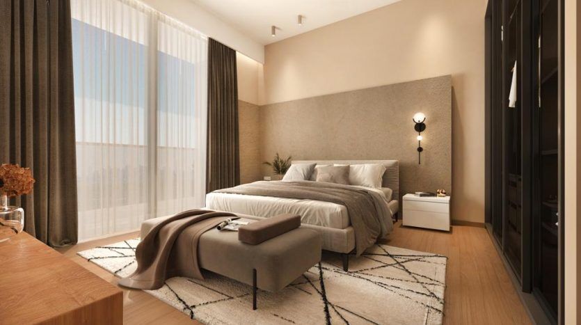 Une chambre moderne dans une villa à Dubaï avec un grand lit, une literie grise et blanche, une banquette au pied du lit, du parquet et une grande fenêtre avec des voilages. Tons neutres