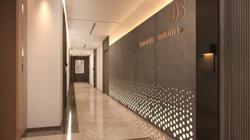 Un couloir d'immeuble moderne à Dubaï avec des sols en marbre poli, des murs éclairés avec des découpes décoratives et des portes marquées de chiffres et de panneaux en anglais et en braille.