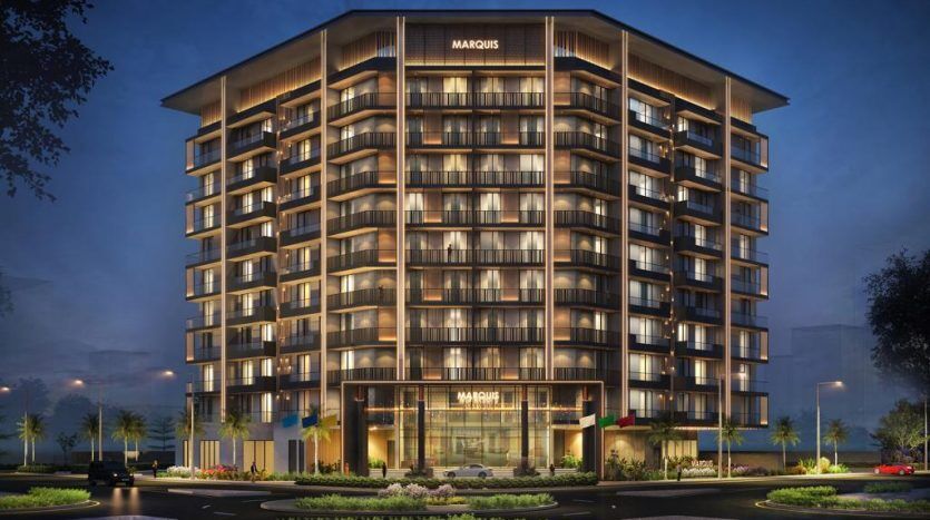 Un rendu numérique d'un immeuble moderne de grande hauteur appelé "Marquis" à Dubaï, éclairé au crépuscule. L'entrée comprend un auvent éclairé, un aménagement paysager élégant, des palmiers et des voitures garées.