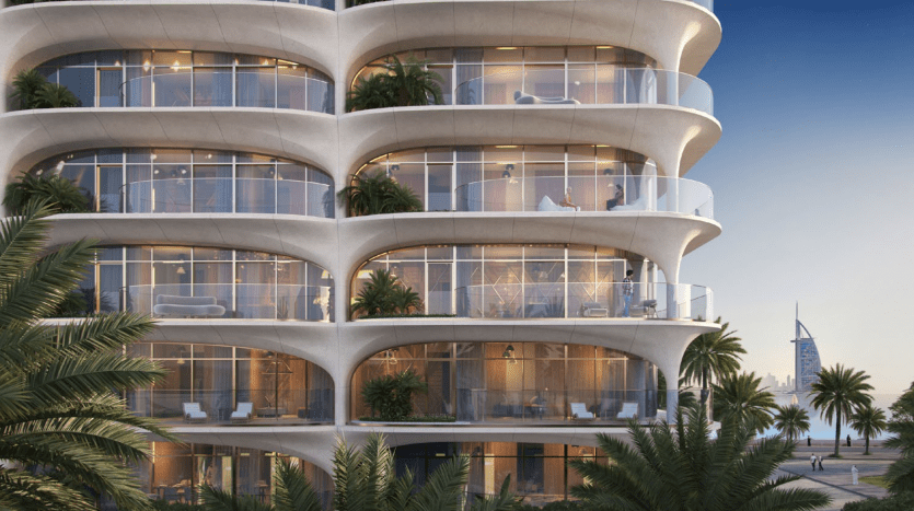 Un bâtiment moderne avec des balcons incurvés, de grandes fenêtres en verre et des palmiers au premier plan, présentant une opportunité d'investissement à Dubaï avec une ligne d'horizon qui inclut le Burj Al Arab au loin.