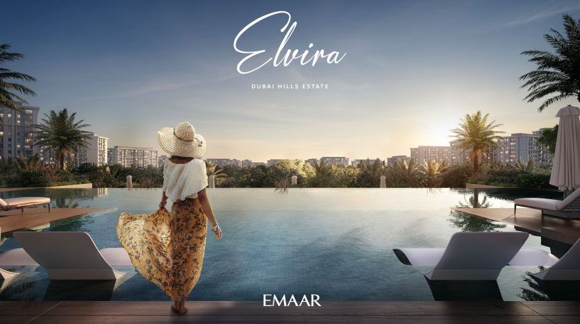 Une femme vêtue d’une robe fluide et d’un chapeau de soleil se tient près d’une piscine à débordement, face à une vue sur les bâtiments modernes de la ville au coucher du soleil. Le texte indique « Elvira, Dubai Hills Estate » et « E