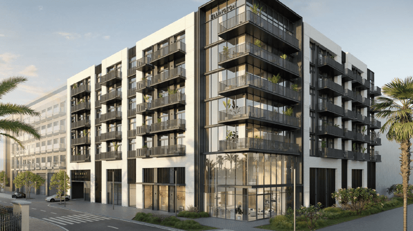 Immeuble d'appartements moderne avec de grandes fenêtres en verre et des balcons, portant le nom « Inizio » au sommet, entouré de palmiers par une journée ensoleillée avec vue sur la rue de Dubaï.