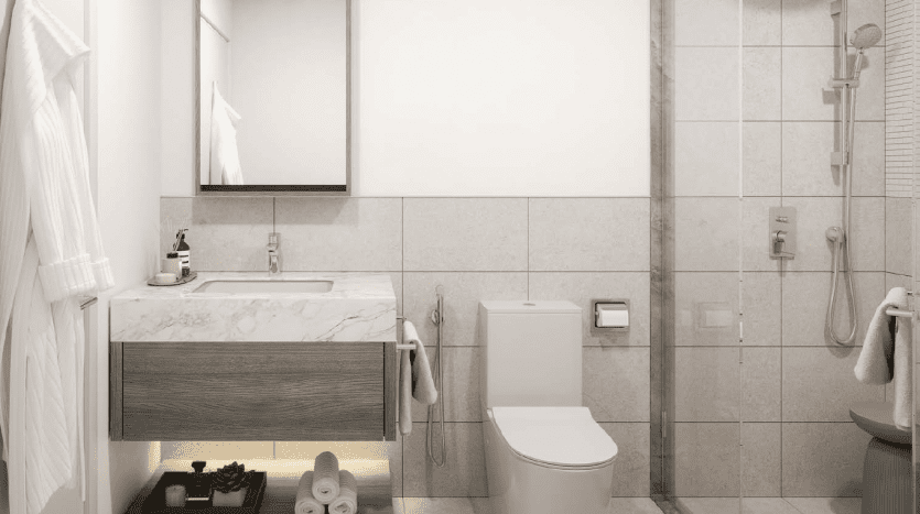 Une salle de bains moderne dans une villa de Dubaï avec une douche en verre, des toilettes blanches et une vanité avec un comptoir en marbre. Il y a des serviettes sur des supports et des articles de toilette soigneusement disposés sous l'évier.