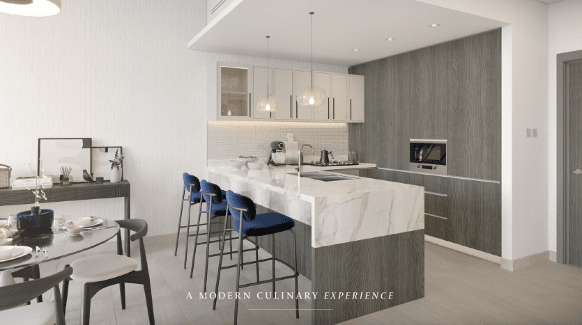 Une cuisine moderne et élégante avec des comptoirs en marbre blanc, des armoires grises et des tabourets de bar bleus dans un bar de petit-déjeuner dans un appartement de Dubaï. Au-dessus se trouvent des suspensions élégantes et le texte « un