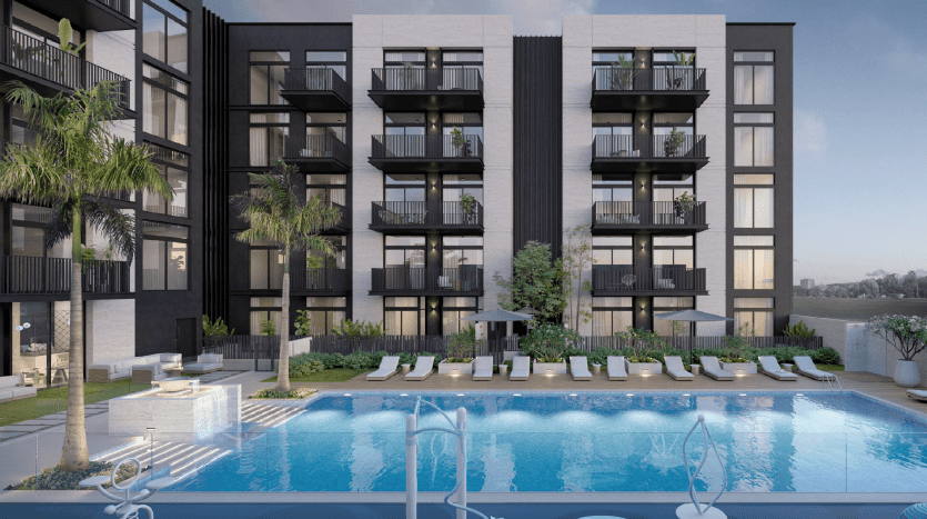 Immeuble d'appartements moderne avec balcons donnant sur une piscine entourée de palmiers, de chaises longues et de fontaines, sur fond de front de mer à Dubaï.