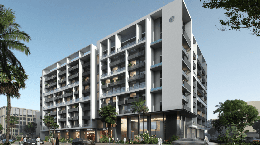 Un immeuble d'appartements contemporain de plusieurs étages à Dubaï avec un design élégant, doté de balcons et de grandes fenêtres. Le rez-de-chaussée accueille des espaces commerciaux. Des personnes et des véhicules sont vus à l’extérieur.