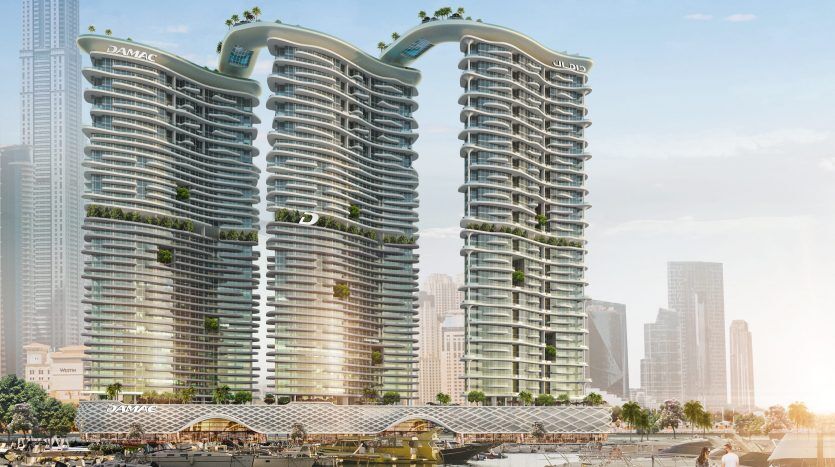 Deux immeubles futuristes de grande hauteur avec des terrasses verdoyantes sur leurs façades surplombent une marina avec des bateaux sous un ciel ensoleillé, situés dans un paysage urbain moderne à Dubaï.