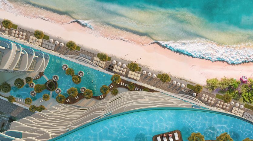 Vue aérienne d'une station balnéaire de luxe à Dubaï avec plusieurs piscines, des jardins luxuriants et une vaste plage de sable bordée par les eaux turquoise de l'océan.