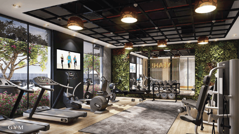 Intérieur de salle de sport moderne comprenant des tapis roulants, des équipements de musculation, un support d'haltères et de grands écrans affichant des tutoriels de fitness. L'espace comprend des murs de verre, de la verdure et un éclairage ambiant. Idéal pour investir