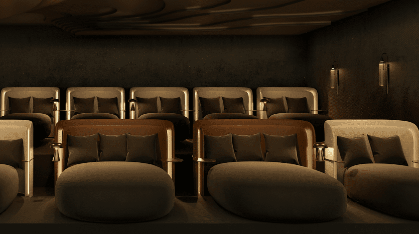 Un home cinéma luxueux aux tons sombres dans une villa de Dubaï avec un éclairage doré, comprenant des rangées de fauteuils marron moelleux associés à des poufs ronds et veloutés, conçus pour le confort et l'esthétique.