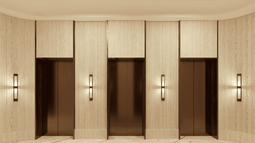 Trois portes d'ascenseur fermées avec une finition marron brillant, situées dans un mur de couleur crème avec des panneaux décoratifs et des appliques lumineuses dans un hall d'entrée moderne de l'immobilier de Dubaï.