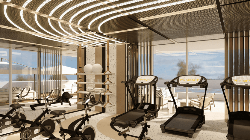 Salle de sport moderne avec divers appareils d'exercice, dont des tapis roulants et des vélos stationnaires, située dans une villa à Dubaï. L'établissement donne sur une plage ensoleillée grâce à de grandes fenêtres. Le décor en bois et les luminaires incurvés rehaussent