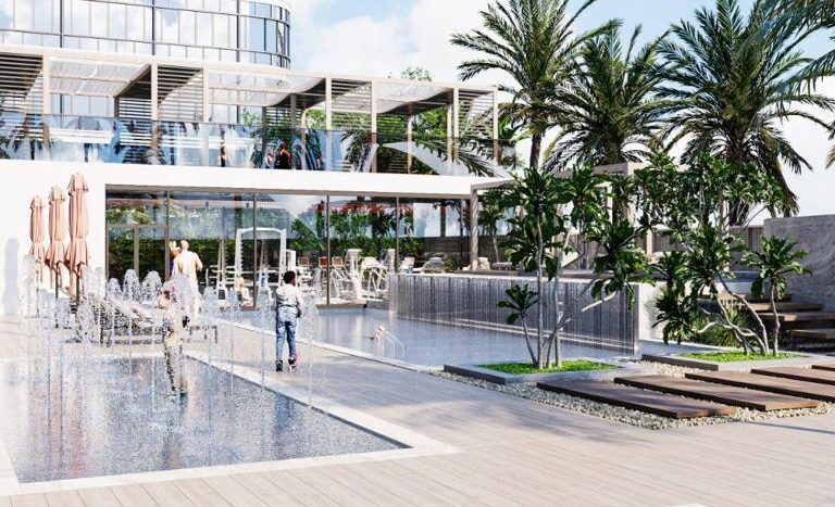 Une piscine de complexe moderne à Dubaï avec des passants et des palmiers, avec des zones d'eau peu profonde, des chaises longues sous des parasols ouverts et un bâtiment à plusieurs étages en arrière-plan.