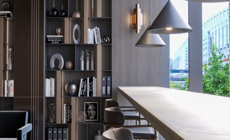 Une salle de repos de bureau moderne dans un appartement de Dubaï comprenant un long comptoir en béton, des tabourets hauts et de grandes étagères remplies de livres et d'objets de décoration. De grandes suspensions sont suspendues au-dessus, avec vue sur la ville