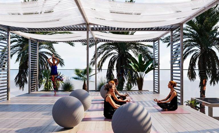 Deux personnes pratiquent le yoga sur des tapis dans un pavillon moderne en plein air aux poutres blanches, entouré de palmiers luxuriants et de sculptures sphériques, sous un toit ensoleillé à motifs dans une prestigieuse villa de Dubaï.