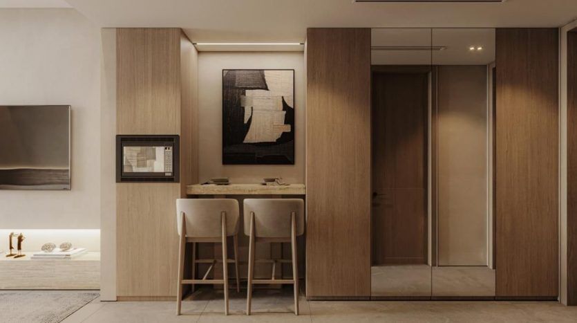 Coin repas moderne et minimaliste dans un appartement de Dubaï avec une table en bois et deux chaises, flanquées d'armoires en bois et d'œuvres d'art abstraites sur les murs, sous un éclairage chaleureux.