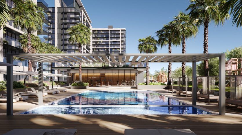 Un espace piscine extérieur luxueux, doté de chaises longues élégantes et d'une pergola moderne, avec des palmiers et des immeubles de grande hauteur en arrière-plan sous un ciel dégagé à Dubaï.