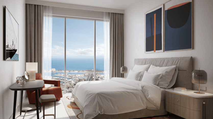 Modernes Zimmer mit einem großen Fenster mit Meerblick, perfekt für Investitionen in Dubai, bestehend aus einem Doppelbett, Kunstwerken an der Wand und einer Arbeitsecke mit einem Schreibtisch und einem roten Stuhl.