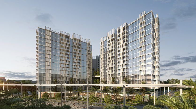 Des gratte-ciels modernes en verre jumeau nichés au milieu d'une verdure luxuriante avec une passerelle piétonne et un parc au premier plan sous un ciel bleu clair à Dubaï.