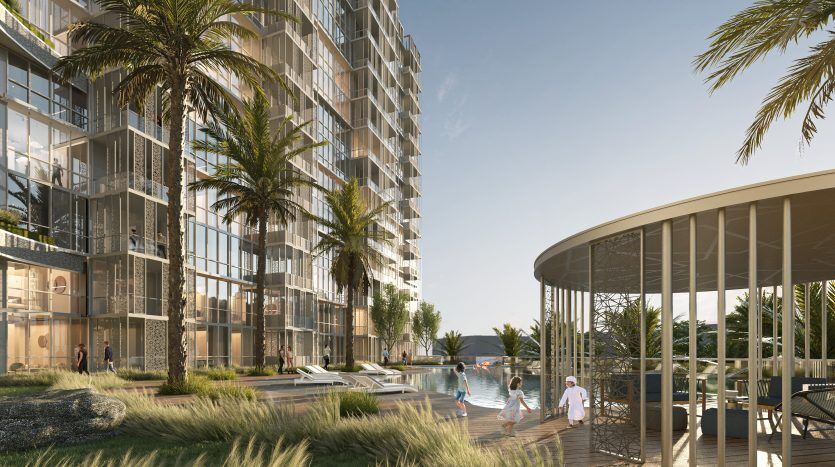 Un gratte-ciel luxueux en bord de mer à Dubaï avec un aménagement paysager luxuriant et une piscine sereine, avec des gens profitant du soleil, des palmiers et un pavillon moderne.
