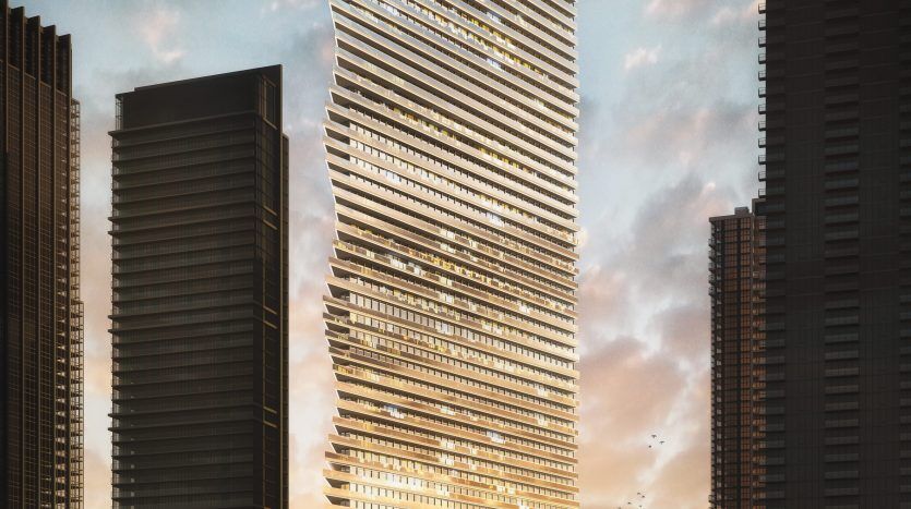 Un gratte-ciel moderne au design unique et torsadé, éclairé par le soleil couchant, aux côtés d'autres grands immeubles au bord d'un front de mer à Dubaï, avec un yacht qui passe par là.