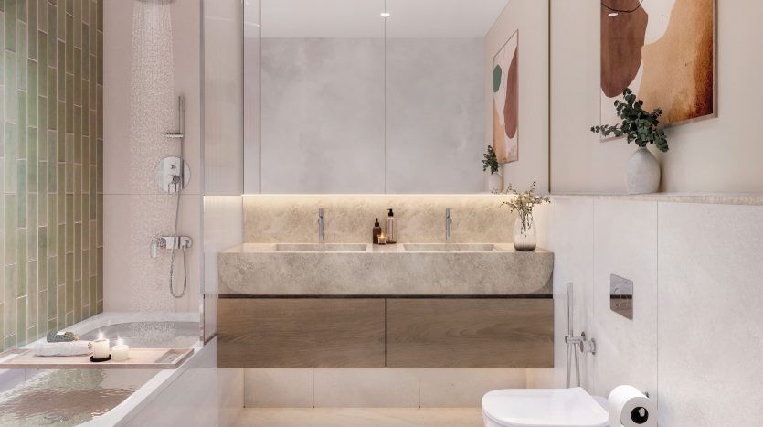 Une salle de bains moderne et spacieuse dans un appartement de Dubaï comprenant une baignoire, une cabine de douche en verre, des toilettes murales et du carrelage aux tons terre. Le décor comprend de l'art abstrait, des plantes vertes et un éclairage tamisé.