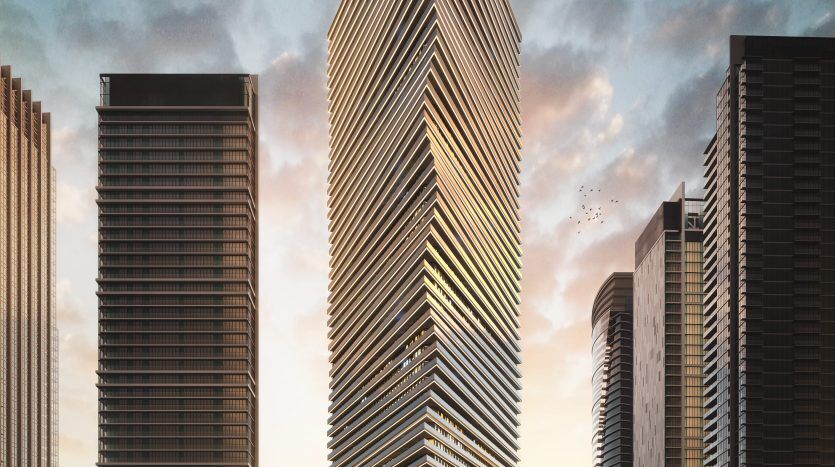 Un imposant gratte-ciel moderne, conçu avec des lignes angulaires nettes et de multiples balcons à facettes en verre, se dresse majestueusement au crépuscule. Entourée d'autres immeubles de grande hauteur à Dubaï, sa façade est