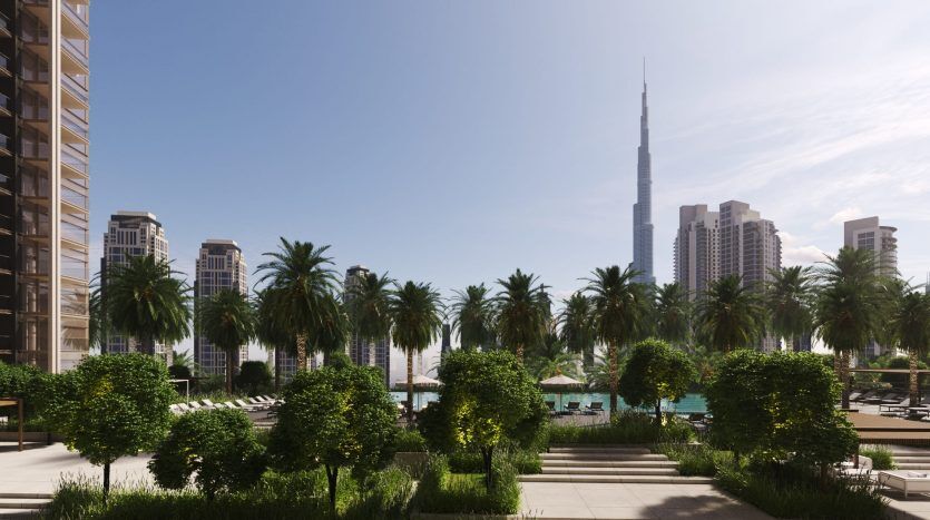 Un paysage urbain ensoleillé avec un parc luxuriant avec des rangées de palmiers et des buissons bien entretenus, flanqué d'immeubles de grande hauteur sous un ciel bleu clair. En arrière-plan, un gratte-ciel imposant à Dubaï