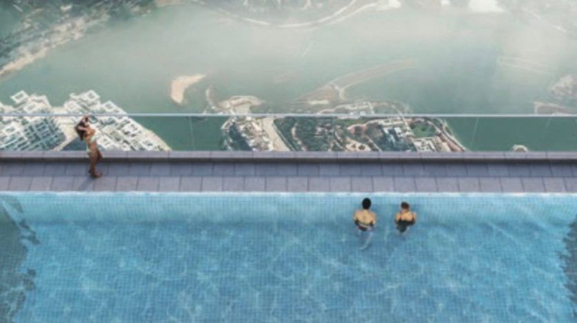 Vue aérienne d'une piscine à débordement sur le toit surplombant un paysage urbain avec des rivières et des espaces verts, montrant plusieurs personnes profitant de la piscine à Dubaï.