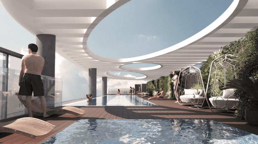 Une luxueuse piscine sur le toit avec un homme debout au bord, des gens se prélassant dans des cabanes, entourées de plantes luxuriantes, sous une structure architecturale moderne et incurvée ouverte sur un ciel dégagé dans une villa haut de gamme