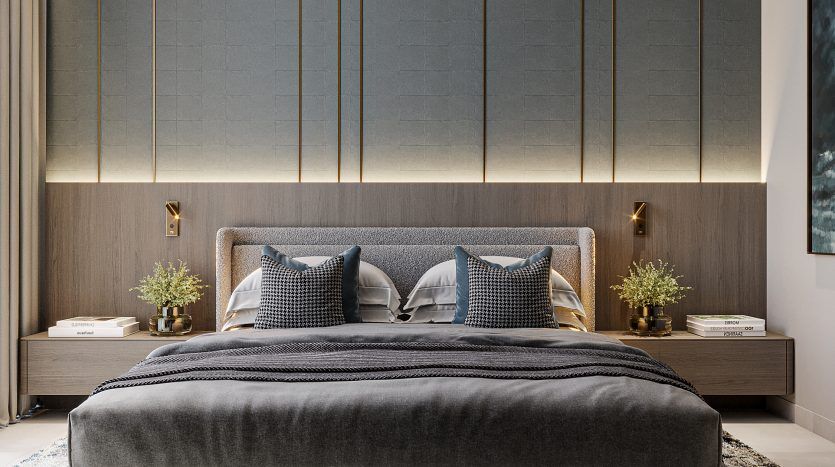 Chambre moderne dans un appartement de Dubaï comprenant un lit gris foncé à profil bas avec des oreillers assortis, flanqué de murs lambrissés aux accents dorés, de petites tables de chevet et d'un plafonnier ramifié unique
