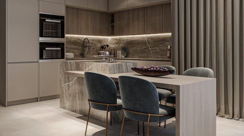 Intérieur de cuisine moderne avec comptoirs en marbre élégants, appareils électroménagers intégrés et coin repas avec chaises grises sous un éclairage tamisé dans une villa de Dubaï.