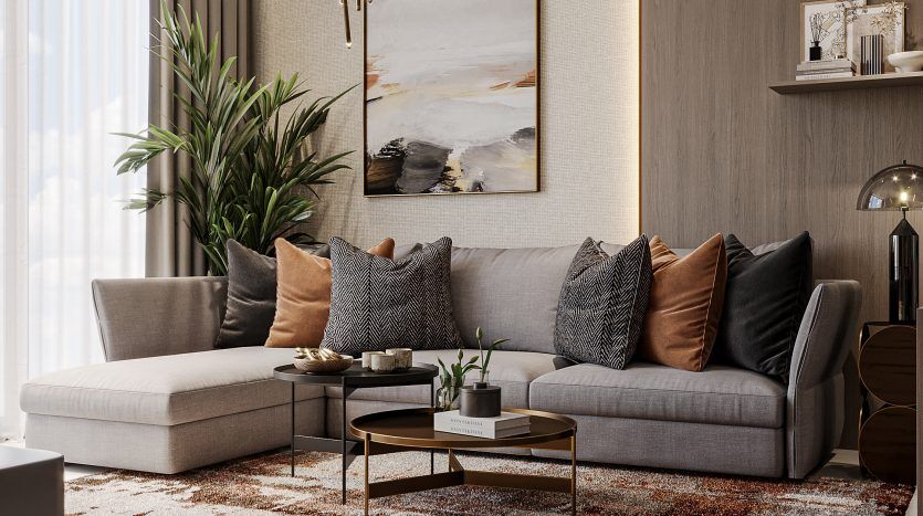 Salon moderne dans un appartement de Dubaï avec un canapé gris sectionnel, un lustre décoratif, un tapis texturé et des œuvres d'art murales, complétés par des plantes d'intérieur et un éclairage naturel.