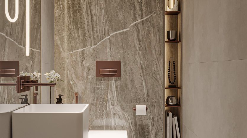 Une salle de bains moderne dans un appartement de Dubaï comprenant une baignoire autonome, des toilettes murales et un grand mur en marbre, avec des étagères intégrées contenant les essentiels et la décoration de la salle de bain.