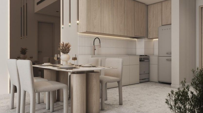 Une cuisine et un coin repas modernes avec des armoires en bois clair, un sol en marbre blanc et une table à manger pour quatre personnes avec des chaises rembourrées sous des suspensions dans une luxueuse villa de Dubaï.